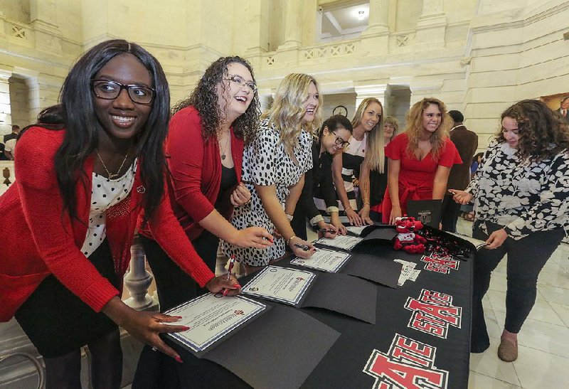 Students sign pledges demonstrating their commitment to education careers at the state Capitol rotunda on Friday afternoon. They are (from left) Taysia Johnson, Kennedy Capps, Ashley Field, Le Kieu Ngo, Taylor Tiffany, Delaney Daniel and Alecea Raymond. They plan to attend Arkansas State University in Jonesboro. The event kicked off the Arkansas Department of Education’s first Educator Commitment Signing Week, to be held starting Sunday to April 20.