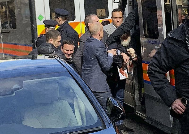 Police rush WikiLeaks founder Julian Assange from the Ecuadorian embassy into a police van in London after he was arrested by officers from the Metropolitan Police and taken into custody Thursday. 