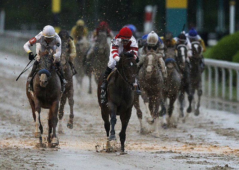 Omaha Beach and jockey Mike Smith (center) cross the line to win Saturday’s 83rd Arkansas Derby at Oaklawn Park in Hot Springs ahead of runner-up Improbable and Jose Ortiz (left). An estimated crowd of 45,000 attended the event despite rainy conditions. See more photos at arkansasonline.com/414derby.