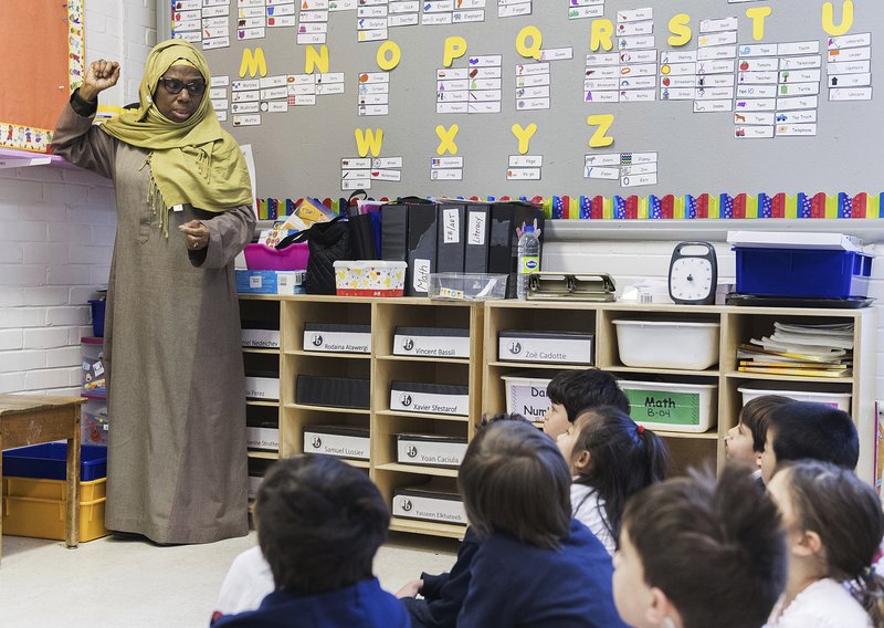 In this Thursday, April 4, 2019, photo, kindergarten teacher Haniyfa Scott gives a lesson during class in Montreal. The Quebec government's recently tabled Bill 21 bans the wearing of religious symbols for new government placed employees within schools, the courts and law enforcement.  (Graham Hughes/The Canadian Press via AP)