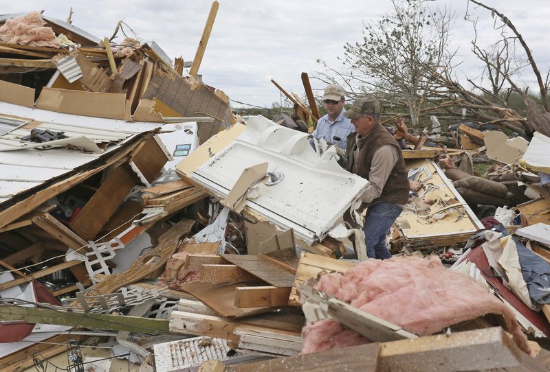 Roman Brown (left) and Sam Crawford move part of a shower wall out of their way as they help a friend look for medicine in their destroyed home Sunday, April 14, 2019, outside of Hamilton, Miss., after an apparent tornado touched down Saturday. (AP Photo/Jim Lytle)