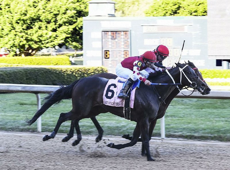 Hall of Fame jockey Mike Smith rides Midnight Bisou (6) past Es- cape Clause and jockey Tyler Baze to win the Apple Blossom Handicap at Oaklawn Park on Sunday.