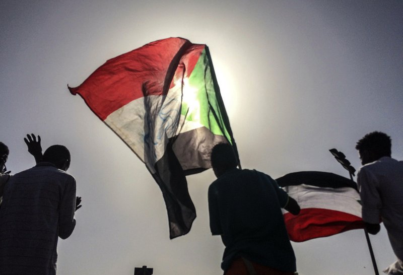 Sudanese demonstrators march with national flags as they gather during a rally demanding a civilian body to lead the transition to democracy, outside the army headquarters in the Sudanese capital Khartoum on Saturday, April 13, 2019.  The military overthrew President Omar al-Bashir on Thursday after almost four months of protests calling for an end to his nearly 30-year rule. (AP Photo)