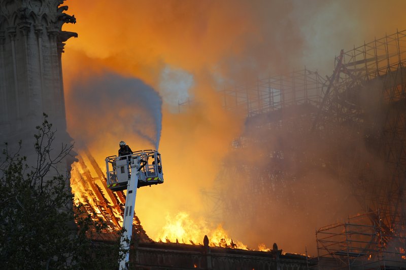 A fire fighter uses a hose as Notre Dame cathedral is burning in Paris, Monday, April 15, 2019. A catastrophic fire engulfed the upper reaches of Paris' soaring Notre Dame Cathedral as it was undergoing renovations Monday, threatening one of the greatest architectural treasures of the Western world as tourists and Parisians looked on aghast from the streets below. (AP Photo/Francois Mori)