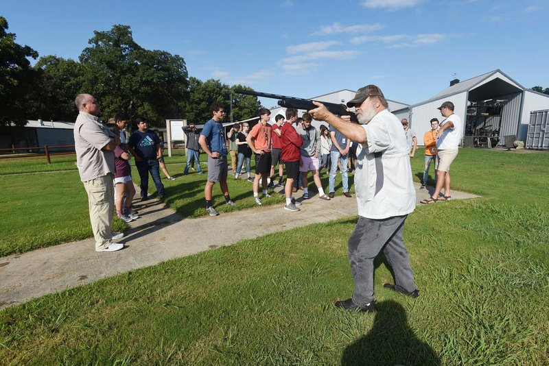 NWA Democrat-Gazette/FLIP PUTTHOFF Lonnie Robinson, volunteer educator with the Arkansas Game and Fish Commission, teaches shotgun skills to Bentonville High School students last year at a private trap-shooting range.