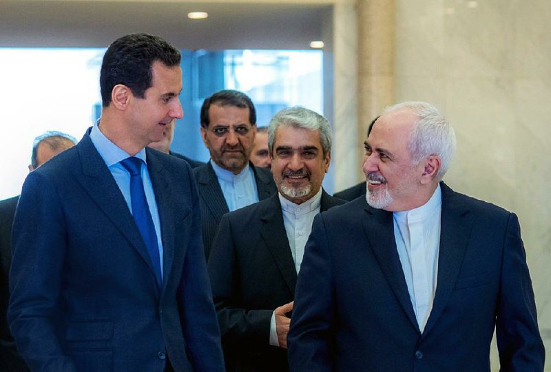 Syrian President Bashar Assad (left) speaks Tuesday with Iranian Foreign Minister Mohammad Javad Zarif in Damascus, Syria. 