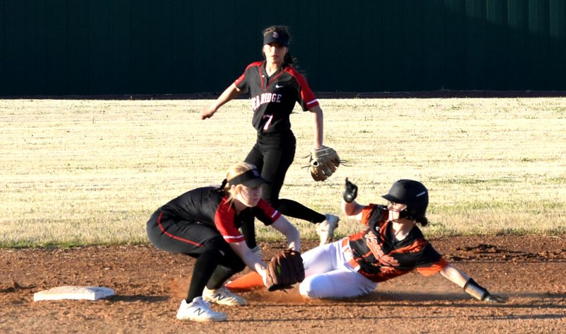 Westside Eagle Observer/MIKE ECKELS As the Lady Blackhawks second baseman waits for the throw from first base, Lizzy Ellis slides into the base during the Gravette-Pea Ridge conference softball game in Gravette April 8. Ellis beat the throw and was safe at second.