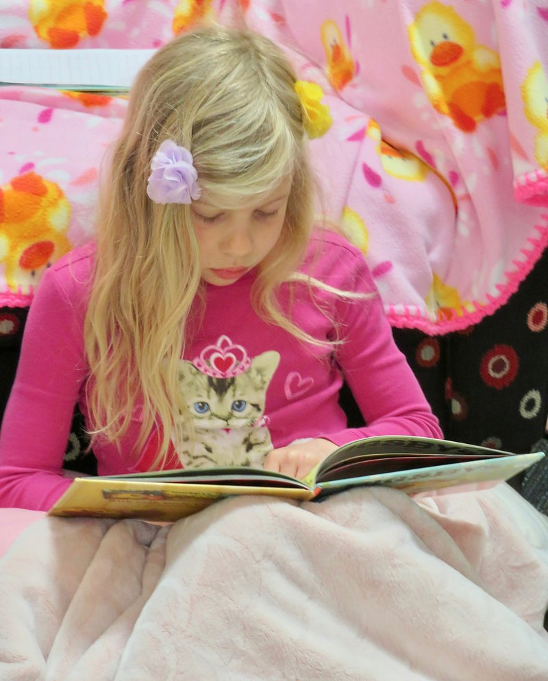 Westside Eagle Observer/RANDY MOLL Lucy Couchenour, 8, from the Gentry's Ozark Adventist School, reads a book at the Gentry Public Library on Friday. The children were reading to raise funds for a mission school in Uganda.