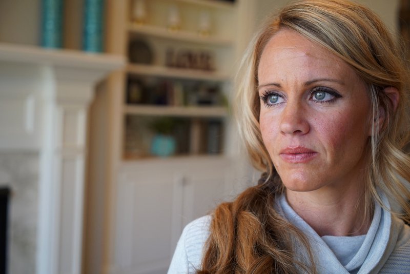 In this March 27, 2019, photo, Kacey Ruegsegger Johnson poses for a portrait at her home in Cary, N.C. Ruegsegger Johnson, now a mother of four, survived a shotgun blast during the 1999 shootings at Colorado's Columbine High School that left 12 students, one teacher, and both gunmen dead. The emotional toll of the shooting, joined by fears about their own kids' safety, spikes each time yet another shooter enters another school. (AP Photo/Allen G. Breed)