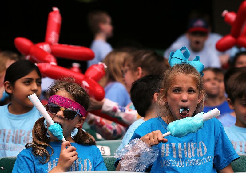 Malaina Rodgers (right) and Josie Sandlin, third-graders at Westside Elementary School in Searcy, munch on cotton candy as they watch the Arkansas Travelers play the Northwest Arkansas Naturals on Wednesday at Dickey-Stephens Park in North Little Rock. See more photos at arkansasonline.com/418travskids/ 