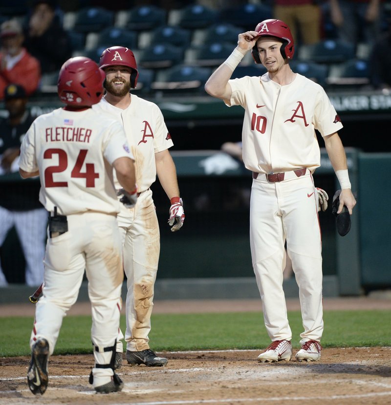 NWA Democrat-Gazette/Andy Shupe PARTY AT THE PLATE: Arkansas center fielder Dominic Fletcher (24) is congratulated Tuesday by second baseman Trevor Ezell and designated hitter Matt Goodheart (10) after hitting a three-run home run in the third inning against Arkansas-Pine Bluff at Baum-Walker Stadium in Fayetteville.