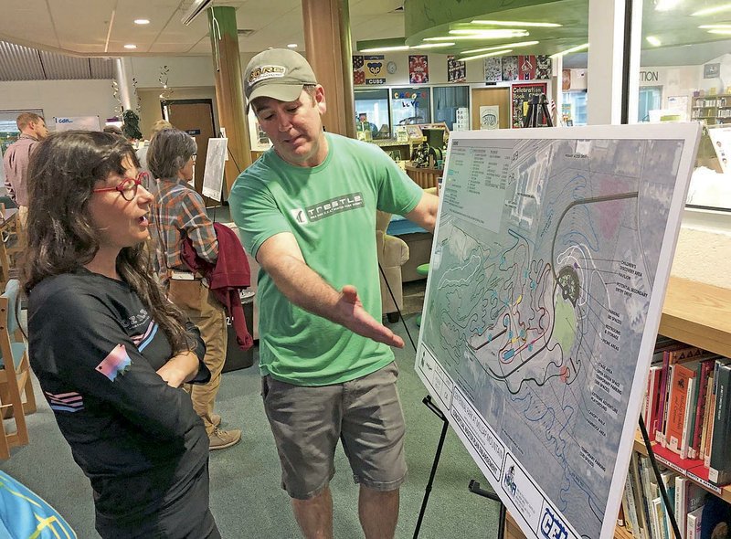 NWA Democrat-Gazette/STACY RYBURN Anya Bruhin (left) with BikeNWA and Rob Reno with Ozark Off-Road Cyclists discuss Wednesday a conceptual map of Centennial Park at Millsap Mountain during a meeting at Owl Creek School in Fayetteville. The city is taking comments to help shape the plan for the park, which is intended to become a mountain-biking attraction.