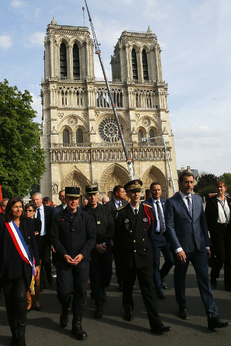 Paris Mayor Ana Maria Hidalgo (left) and French Interior Minister Christophe Castaner (right) walk Thursday with other officials past Notre Dame Cathedral. 