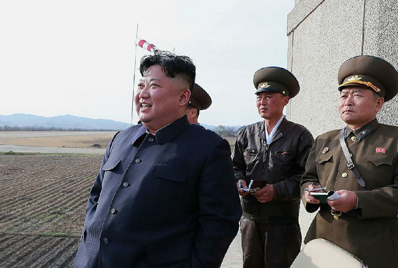 North Korean leader Kim Jong Un (left) stands with military officials at a military airfield Tuesday. Kim reportedly oversaw a test of a new, unspecified tactical weapon. 