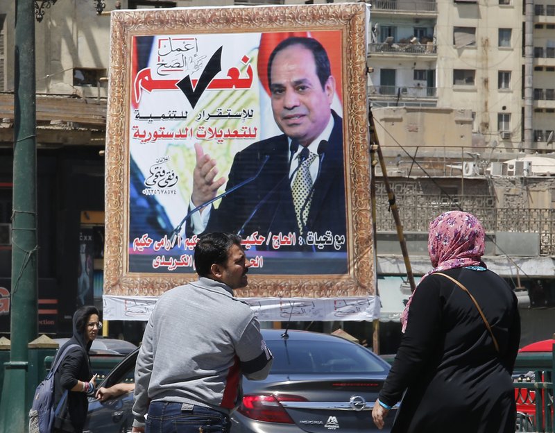 People walk past a banner supporting proposed amendments to the Egyptian constitution with a poster of Egyptian President Abdel-Fattah el-Sissi in Cairo, Egypt, Tuesday, April 16, 2019. Egypt's parliament was holding its last debate Tuesday on proposed amendments to the constitution that could see President Abdel-Fattah el-Sissi remain in power until 2030. Arabic reads, &quot;do the right thing, yes to the developments, stability and amendments to the the constitution&quot;.(AP Photo/Amr Nabil)