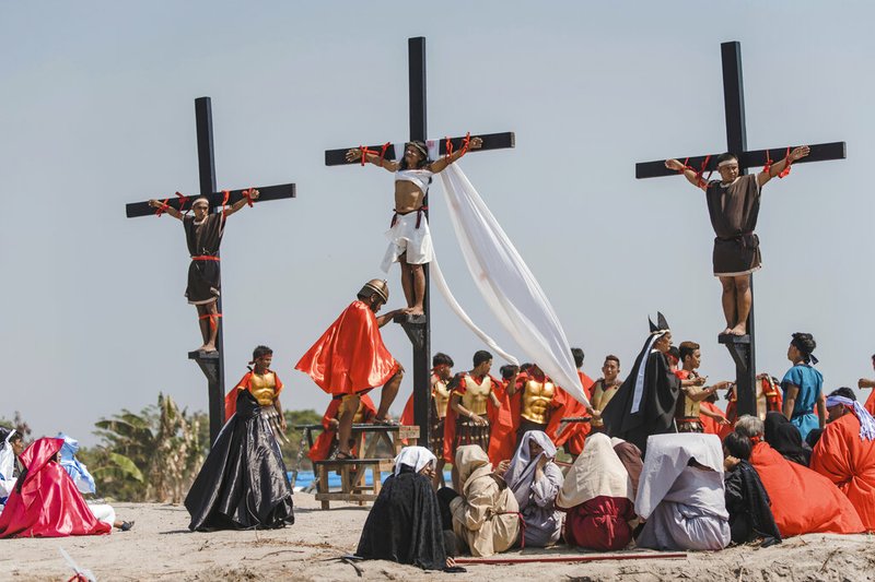 Ruben Enaje, center, dressed as Jesus, is seen nailed on cross for the 33rd year in a row during a reenactment of Jesus Christ's sufferings as part of Good Friday rituals in the village of San Pedro Cutud, Pampanga province, northern Philippines. Friday, April 19, 2019. Over a thousand Filipino Roman Catholic devotees and tourists flocked to a farming village north of Manila on Friday to witness the crucifixion of several devotees in a costumed reenactment of Jesus Christ's sufferings, a gory annual tradition church leaders frown upon. (AP Photo/Iya Forbes)