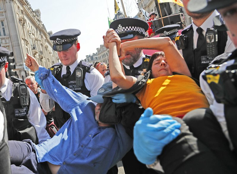 Police arrest a protestor couple who are glued together by their hands, at Oxford Circus in London, Friday, April 19, 2019. The group Extinction Rebellion is calling for a week of civil disobedience against what it says is the failure to tackle the causes of climate change. (AP Photo/Frank Augstein)
