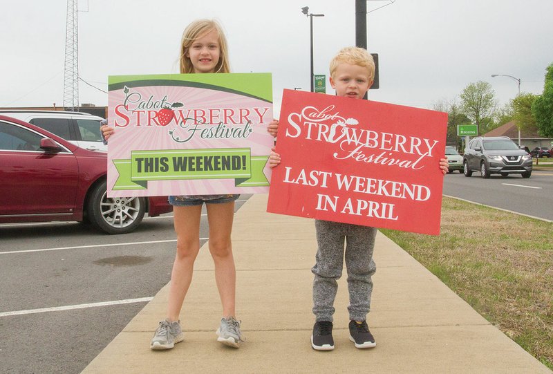 Avery, 6, and Hunter Conley, 4, hold signs promoting the Cabot Junior Auxiliary Strawberry Festival, which starts Friday in downtown Cabot. The Conleys are the children of Allison Conley, public relations chairwoman for the Strawberry Festival.