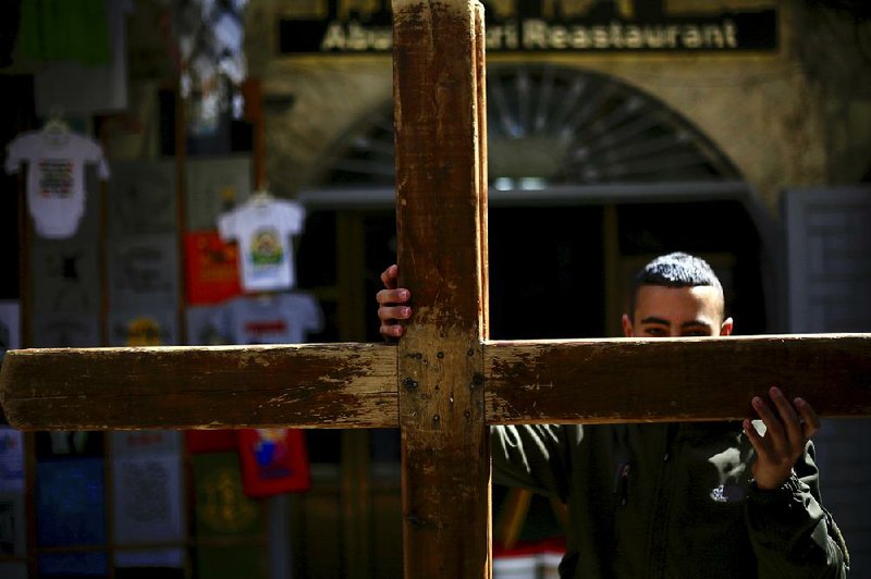 A Christian worshipper in Jerusalem’s Old City carries a cross Friday during a procession along the Via Dolorosa toward the Church of the Holy Sepulchre, traditionally believed to be the site of the crucifixion of Jesus. 