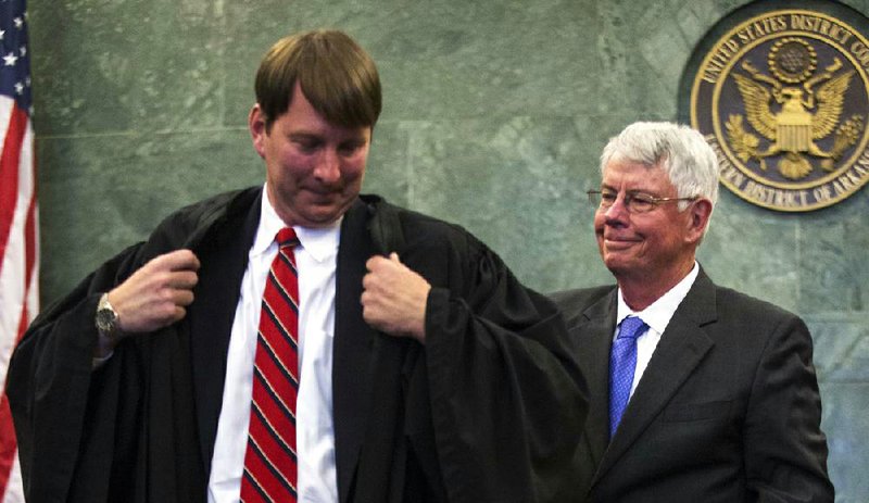 In this file photo U.S. District Judge James Moody Jr. (left) puts on his father’s robe, which the retired James M. Moody Sr. (right) removed after administering the oath of office to his son at the federal courthouse in Little Rock. 