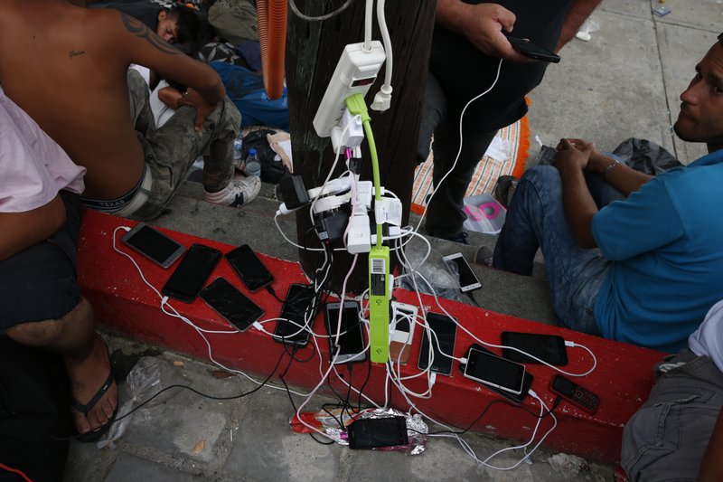 In this Oct. 28, 2018 file photo, migrants charge their cell phones as a caravan of Central Americans trying to reach the U.S. border halts for a rest day in San Pedro Tapanatepec, Oaxaca state, Mexico. Hundreds of Central Americans are now getting as many details as possible before leaving north towards the U.S. border.  (AP Photo/Rebecca Blackwell, File)