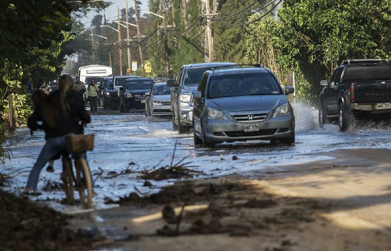 Vehicles travel through surf that washed over a roadway in Haleiwa, a Hawaiian city on the north shore of Oahu, earlier this year. 