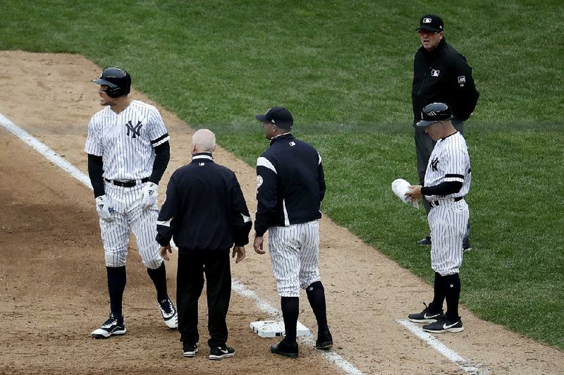 New York Yankees outfielder Aaron Judge (left) reacts while talking to a trainer and bench coach Josh Bard (center) after hitting a single to right field during the sixth inning of Saturday’s 9-2 vic- tory over the Kansas City Royals. Judge was placed on the injured list after straining his oblique muscle on the play.