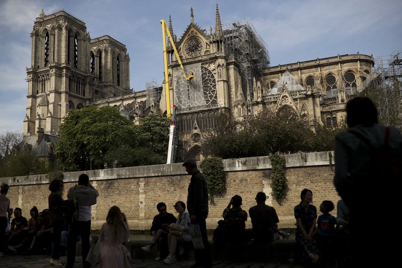 Workers, top, fix a net to cover one of the iconic stained glass windows of the Notre Dame Cathedral in Paris, Sunday, April 21, 2019. The fire that engulfed Notre Dame during Holy Week forced worshippers to find other places to attend Easter services, and the Paris diocese invited them to join Sunday's Mass at the grandiose Saint-Eustache Church on the Right Bank of the Seine River. (AP Photo/Francisco Seco)