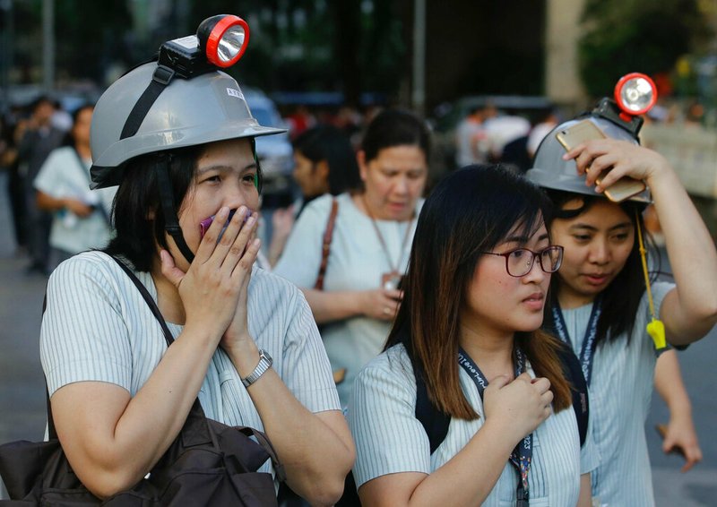 Wearing protective helmets, employees evacuate their office building following an earthquake in Manila, Philippines Monday, April 22, 2019. A strong earthquake has shaken the area around the Philippine capital, prompting thousands of people to flee to safety. There were no immediate reports of injuries or widespread damage. The U.S. Geological Survey says the magnitude 6.3 quake struck northwest of Manila near the town of Gutad on Luzon island. (AP Photo/Aaron Favila)