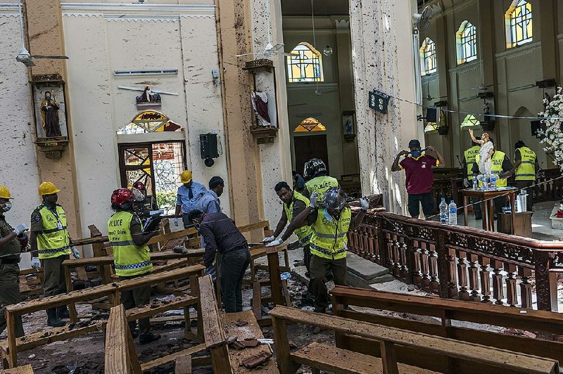 Investigators in Negombo, Sri Lanka, on Monday study the scene of a suicide bombing at St. Sebastian Church. 
