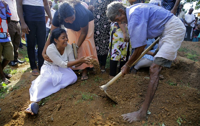 Wasanthi, a member of Berlington family weeps over the gave of Bevon, who was killed in the Easter Sunday bombings in Colombo, Sri Lanka, Tuesday, April 23, 2019. The six near-simultaneous attacks on three churches and three luxury hotels and three related blasts later Sunday were the South Asian island nation's deadliest violence in a decade while Sri Lanka police arrested 40 suspects in the wake of a state of emergency that took effect Tuesday giving the military war-time powers. (AP Photo/Eranga Jayawardena)