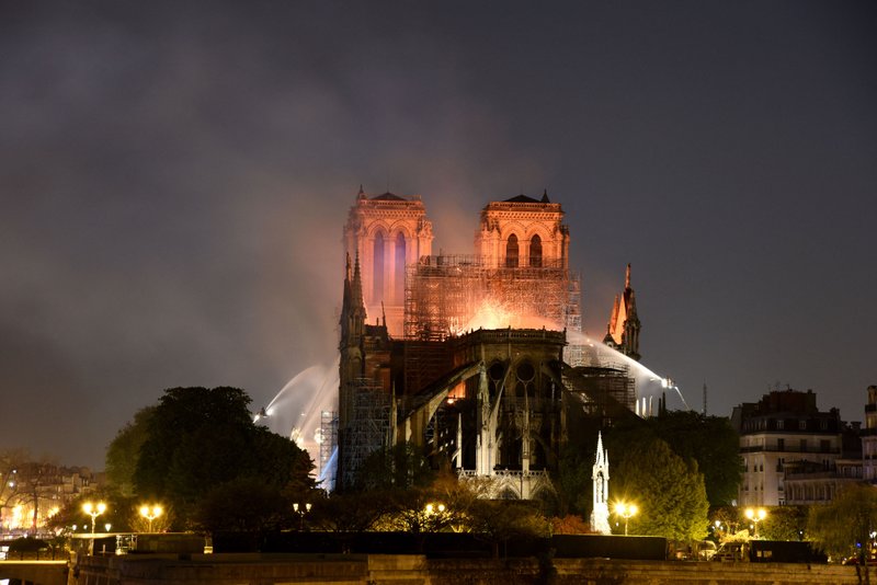 Smoke and flames rise from Notre Dame in Paris, France. The flames and smoke plumed from the spire and roof of the gothic cathedral. 