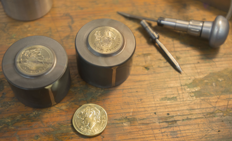 A freshly minted Lannister coin is shown next to it's die at the Shire Post Mint in Springdale. The company makes collectable coins based on several fantasy novels, including George R.R. Martin's "Game of Thrones." (NWA Democrat-Gazette/J.T. WAMPLER)

