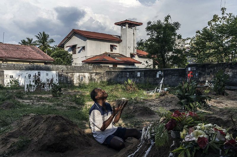 Mourner Melton Roy prays Tuesday among the graves for some of Sunday’s bombing victims during burials at Sellakanda Catholic Cemetery in Negombo, Sri Lanka. 