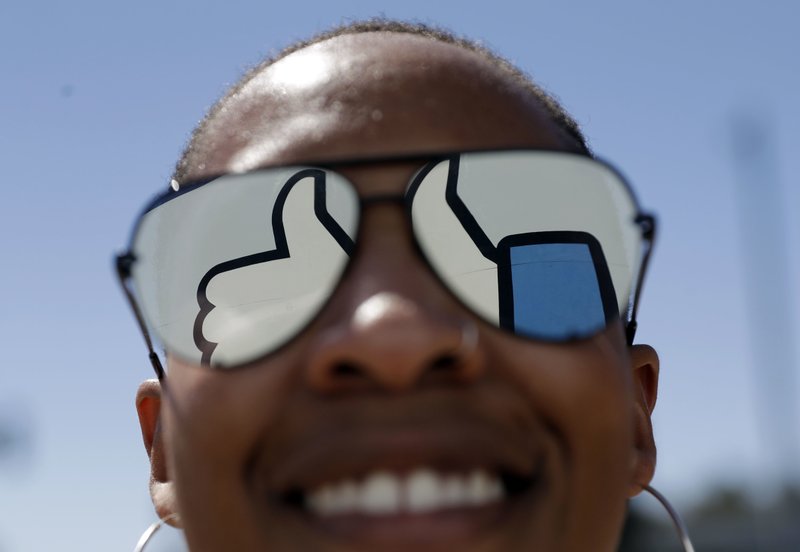 FILE - In this March 28, 2018, file photo, a visitor poses for a photo with the Facebook logo reflected on her sunglasses at the company's headquarters in Menlo Park, Calif. Facebook reports earnings Wednesday, April 24, 2019. (AP Photo/Marcio Jose Sanchez, File)

