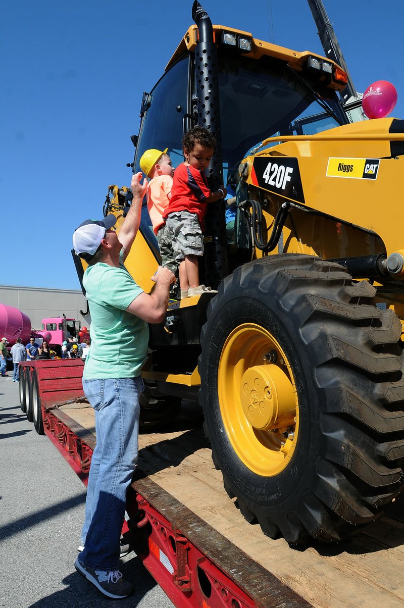 Gary Holland (left) helps his son Tommy as well as Owen Paul (right) climb on a backhoe during a previous Touch A Truck event sponsored by the Junior League of Northwest Arkansas. Big rigs, construction equipment, fire trucks and more will again be on hand Aug. 15 at Pinnacle Hills Promenade in Rogers for youngster and adults to see and touch.
(NWA Democrat-Gazette File Photo/Flip Putthoff)