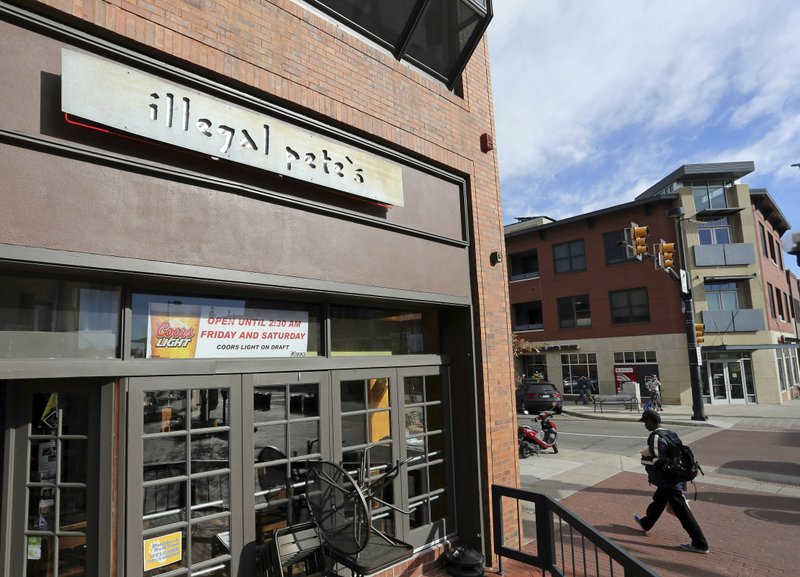 In this Oct. 23, 2014, file photo, a man walks past an Illegal Pete's restaurant in Boulder, Colo.  (AP Photo/Brennan Linsley, File)