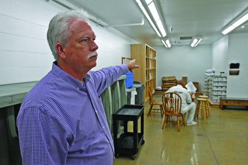 Jail: Union County Sheriff Ricky Roberts (foreground) points out the area of the Union County jail’s kitchen that was damaged in a fire last August. The area has since been renovated; a wall was removed and storage added. An inmate can be seen labeling lunch trays for other inmates with dietary restrictions. Terrance Armstard/News-Times