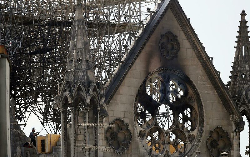 A worker checks on a wooden support structure placed on the Notre Dame Cathedral in Paris recently. Nearly $1 billion has already poured in from ordinary worshippers and high-powered magnates around the world to restore the cathedral after a massive fire. 