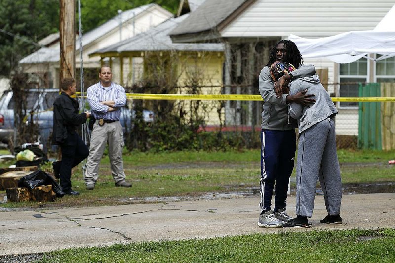 Two people hug Thursday as police investigate a shooting death at a house in the 600 block of West 18th Street in North Little Rock.