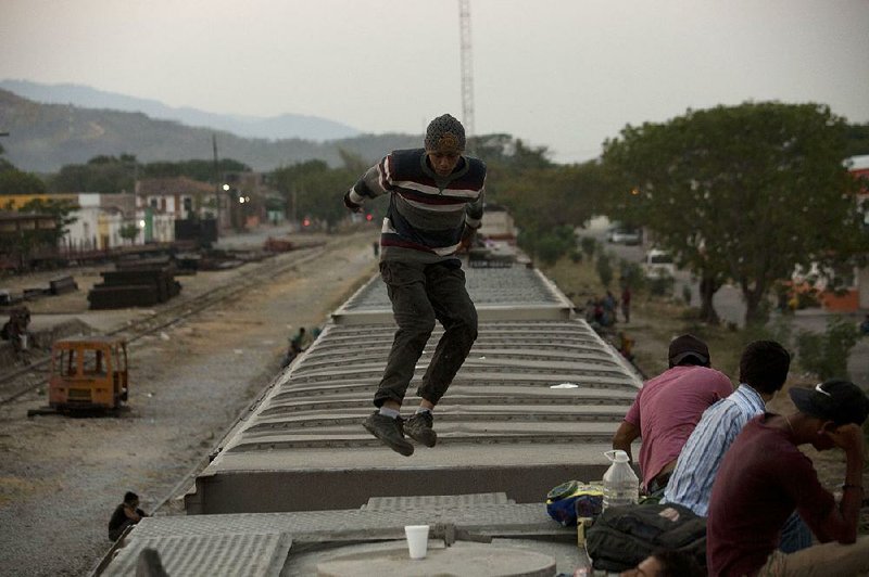 A Central American migrant jumps between freight cars Thursday in Arriaga, Chiapas State, Mexico, on a train headed to the U.S.-Mexico border.