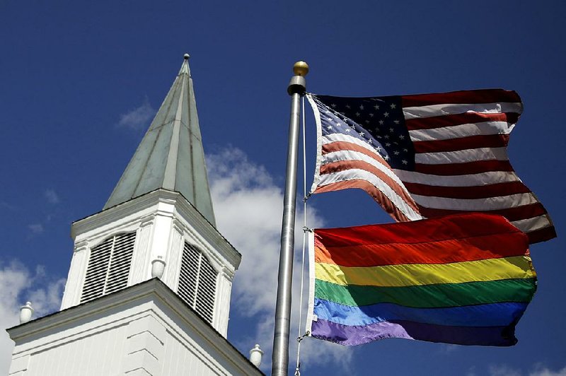 A gay-pride flag flies with the American flag in front of Asbury United Methodist Church in Prairie Village, Kan., last week. While the church has moved to strengthen bans on same-sex marriage and disallow gay and transgender clergy, dissenting members have called for an upsurge of resistance. 