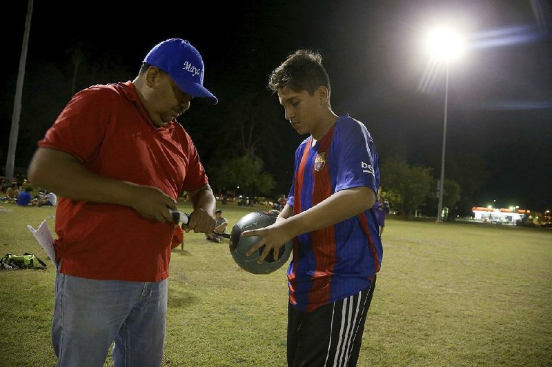 Antonio Velasquez (left), founder of the Maya Chapin soccer organization, inflates a ball earlier this month before a game in Phoenix. 