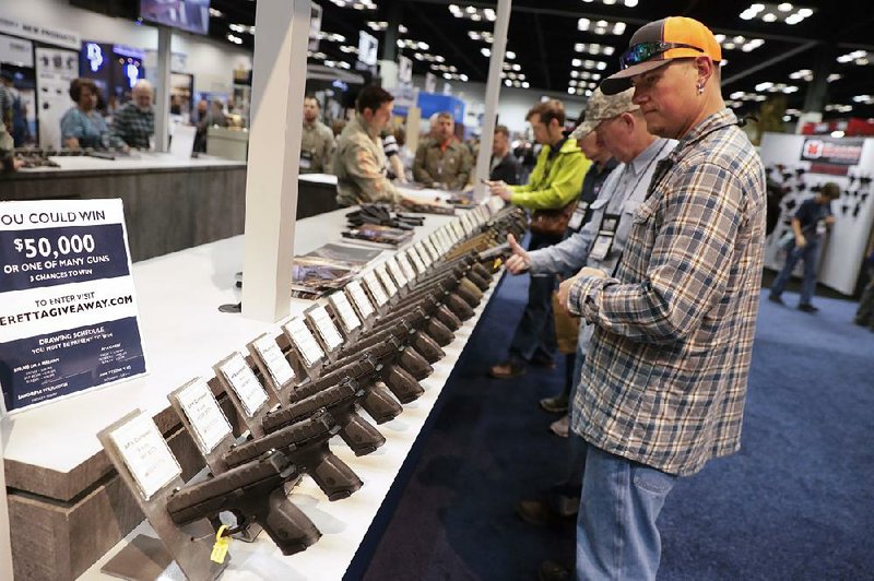 A man looks at a display of Beretta pistols Saturday in the exhibition hall at the National Rifle Association’s convention in Indianapolis. 