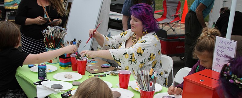 The Sentinel-Record/Tanner Newton ART SHERPA: Cinnamon Cooney, also known as The Art Sherpa, paints kindness rocks with fans and festivalgoers Saturday in Hill Wheatley Plaza during Arts & The Park.