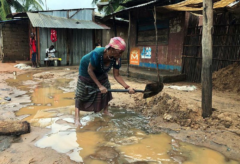 A woman in Pemba, Mozambique, creates a drainage system near her shop Sunday to clear away floodwaters caused by heavy rains. 