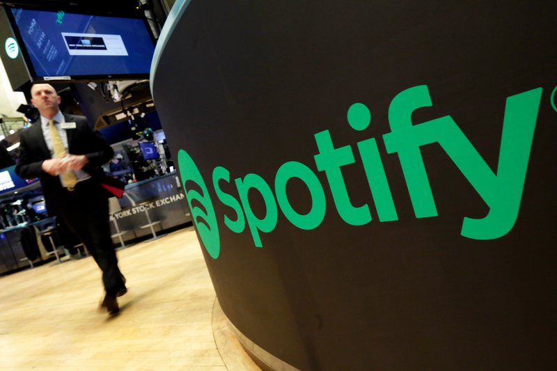 FILE - In this Tuesday, April 3, 2018 file photo, a trading post sports the Spotify logo on the floor of the New York Stock Exchange. Music streaming service Spotify says the number of its paying subscribers has hit 100 million for the first time, up 32% on the year and almost twice the latest figures for Apple Music. The Stockholm-based company called the figure, which was reached during the first three months of 2019, &quot;an important milestone.&quot; (AP Photo/Richard Drew, File)