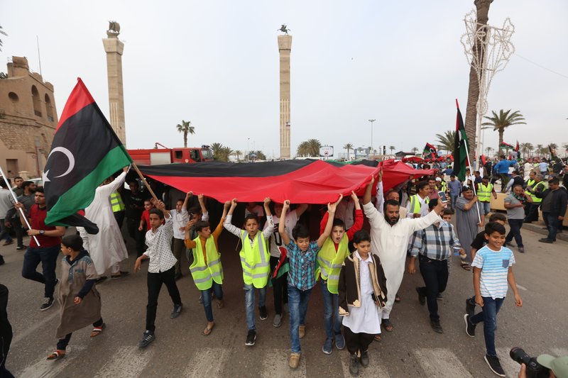 FILE - In this Friday, April 26, 2019, file, photo, protesters march against military operations by Field Marshal Khalifa Hifter's forces in Martyrs' Square on in Tripoli, Libya. Libyan forces loyal to a former military commander have intensified their airstrikes on Tripoli, where heavy fighting and blocked roads have left civilians trapped in their homes, officials said Monday.(AP Photo/Hazem Ahmed, File)