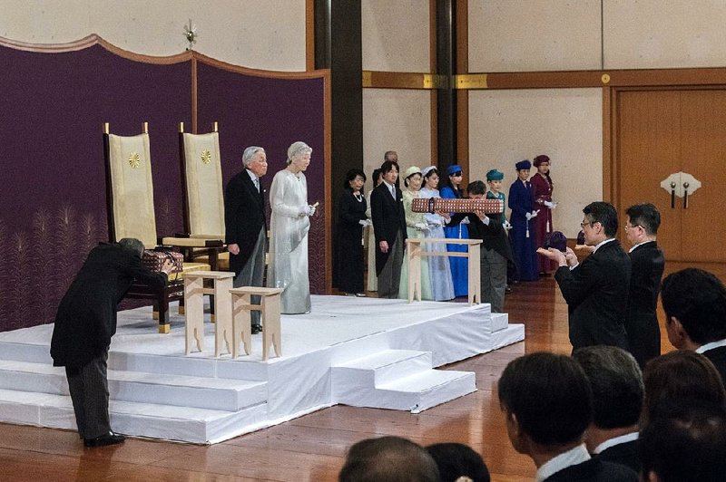 Japanese Emperor Akihito and Empress Michiko stand onstage Tuesday near members of the royal family and top government officials in Tokyo.