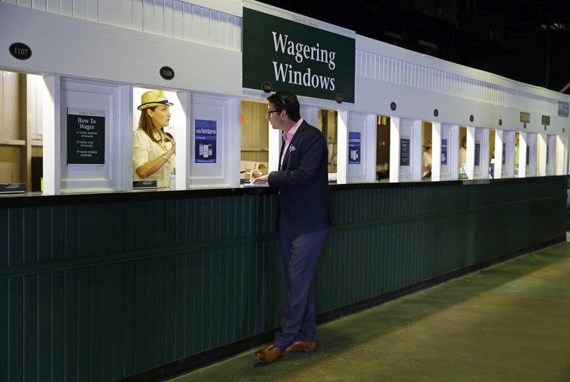 In this May 2, 2015, file photo, a man places a bet before the 141st running of the Kentucky Derby horse race at Churchill Downs, in Louisville, Ky. Picking a horse to win the Kentucky Derby is easy. Hoping that choice wins and pays off with a profit is the challenge.(AP Photo/Jeff Roberson, File)